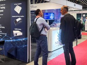 Attendees discussing innovations at the NSTIC (GaN) booth during European Microwave Week 2025 in Utrecht.